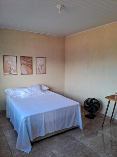 a bedroom with a white bed and a table at Casa 2 quartos perto Centro Ipatinga e aeroporto in Santana do Paraíso