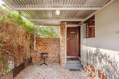 a brick house with a wooden door and a brick wall at Self-catering Garden Cottage in Oudtshoorn