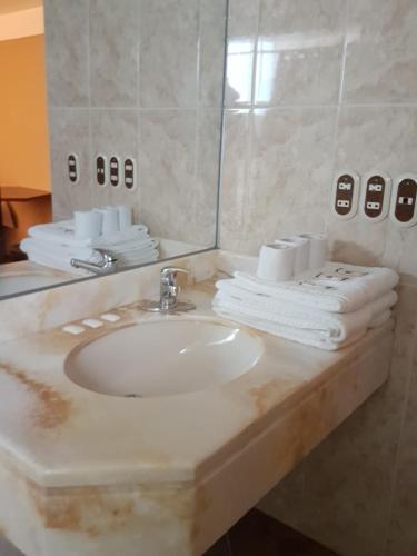 a bathroom with a sink and a mirror and towels at Cordelius Hotel in Puno