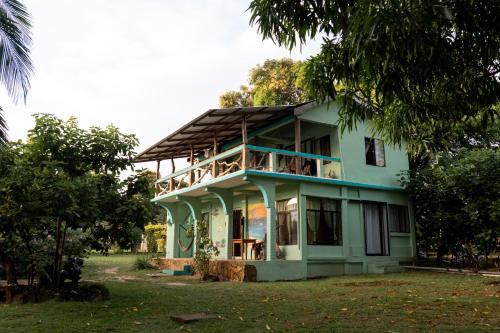 a green house with people on the balcony at Guesthouse Island Escape in Corn Islands