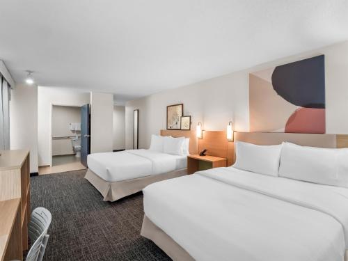 a hotel room with two beds and a tv at Spark By Hilton Ann Arbor South in Ann Arbor