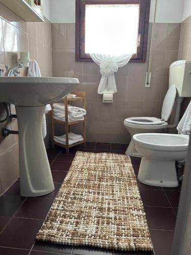 a bathroom with a sink and a toilet and a rug at La Terrazza sul Delta in Porto Levante