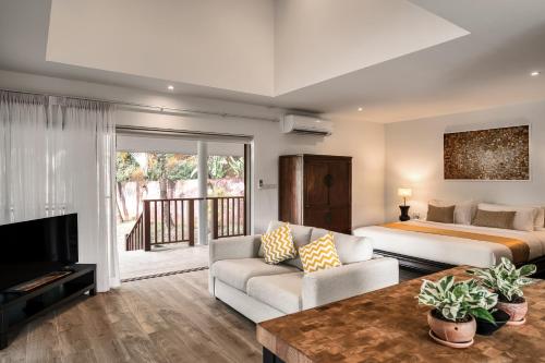 a bedroom with a bed and a couch and a tv at Sontaya - Lakeside Studio Villa in Ban Khao Thong