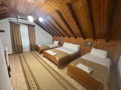 a bedroom with two beds in a room with wooden ceilings at Guest House Argjiro Castle in Gjirokastër