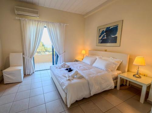 a bedroom with a large white bed and a window at Seliandros Aura Villa in Dhiminión