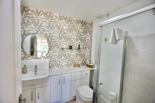 a bathroom with a toilet and a sink and a mirror at The Paddock at Peacock Farm near Belvoir Castle in Redmile