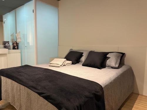 a bedroom with a large bed with black pillows at Studio aconchegante in Belo Horizonte