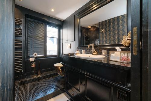 a black bathroom with a sink and a mirror at Le Boudoir in Lyon
