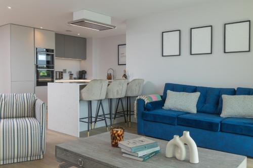 a living room with a blue couch and a kitchen at Luxury Sea View Apartments in Bude with Garden, Sleep 6 in Bude