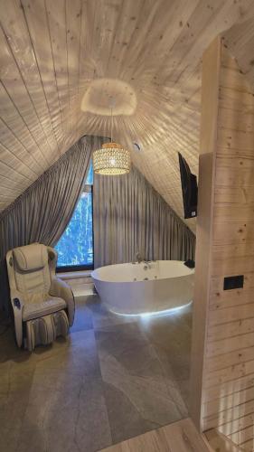 a large bathroom with a tub and a chair at Dadaj Chill 2 domek nad jeziorem, wanna jakuzzi, fotel masujący in Wilimy
