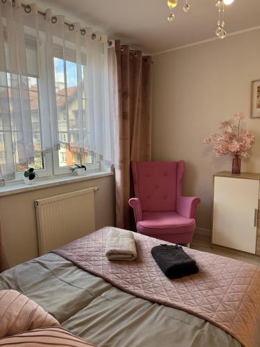 a bedroom with a bed and a pink chair at Apartament Lake Piastowska in Ostróda