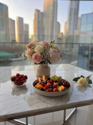 a table with a bowl of fruit and a vase of flowers at London Canary Wharf Luxury Stay in London
