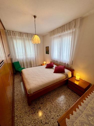 a bedroom with a bed with red pillows and a window at Casa Aurea Lake Como Apartment in Esino Lario