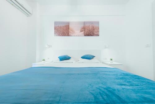 a white bedroom with a large blue bed at TiLiA Breeze Studio Saturn in Saturn