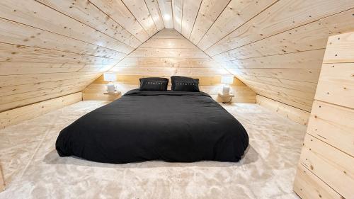 a large black bed in a wooden room at Cottage de luxe en bois in Longnes