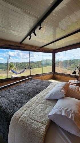 a large bed in a room with a large window at Cabana do Retiro Refúgio Rústico na Natureza! in Alto da Conceição