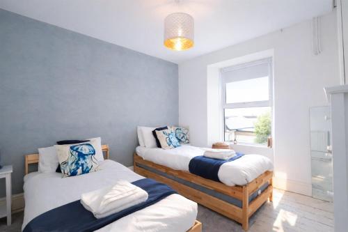 a bedroom with two beds and a window at Palm Haven House - Luxury family-friendly Newquay surf house near Porth Beach perfect for walking, pets, exploring in Newquay