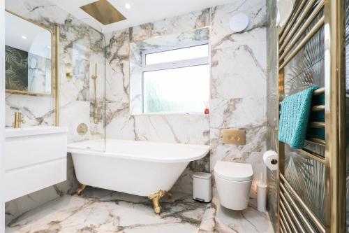 a bathroom with a tub and a toilet and a sink at Palm Haven House - Luxury family-friendly Newquay surf house near Porth Beach perfect for walking, pets, exploring in Newquay