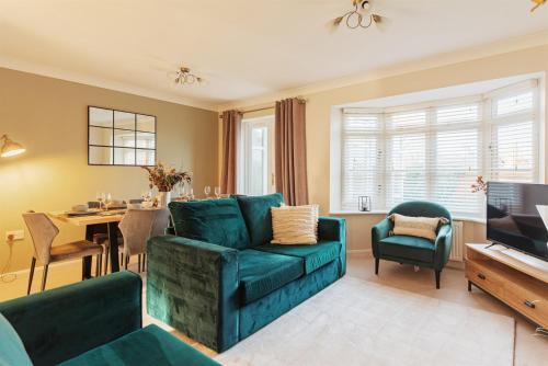 a living room with a green couch and a dining room at 4 Bedroom House in Shrewsbury in Shrewsbury