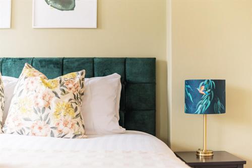 a bed with a green headboard and a lamp at 4 Bedroom House in Shrewsbury in Shrewsbury