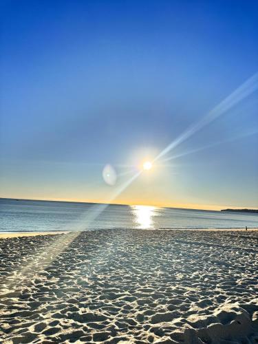 a beach with the sun rising over the water at Sol e Piscina na Caparica - By Caparica Villas in Costa da Caparica