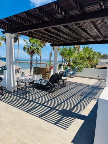 a pavilion with benches and a beach with palm trees at BAJA MÍA in Loreto