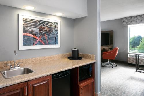 a kitchen with a sink and a desk with a chair at Hampton Inn & Suites West Bend in West Bend