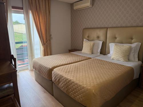 a hotel room with two beds and a window at Hotel Estalagem Turismo in Bragança