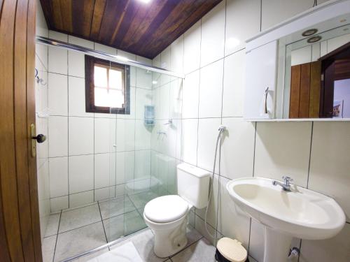a white bathroom with a toilet and a sink at Pousada Canto do Curió Paraty in Paraty