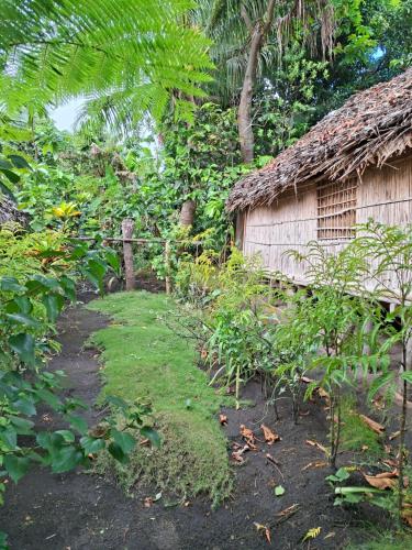 a garden with a house and a yard withgrass at Ash and Ocean BUNGALOW in Loméméti