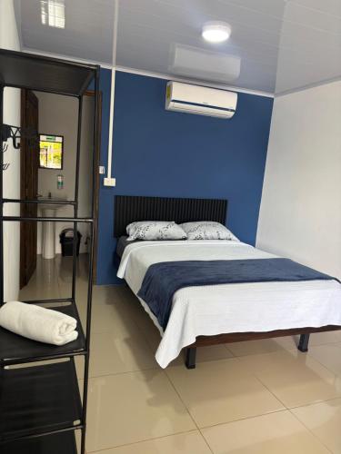 a bedroom with a blue wall and a bed at Centro Turístico Las Palmitas in Muelle del Arenal