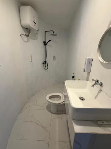 a white bathroom with a sink and a toilet at Highland Bali in Baturaja