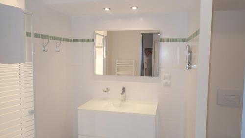 a white bathroom with a sink and a mirror at Résidence Le Beau Site in Capvern