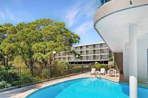 a swimming pool in front of a building at BEST WESTERN PLUS Apollo Hotel Newcastle in Newcastle