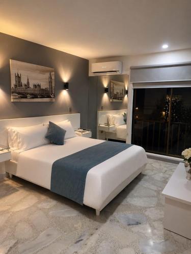 a bedroom with a large white bed and a large window at Hotel Casa Esmeralda in Cali