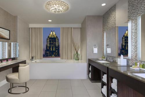 a bathroom with a tub and a sink and a chair at Hilton Austin in Austin