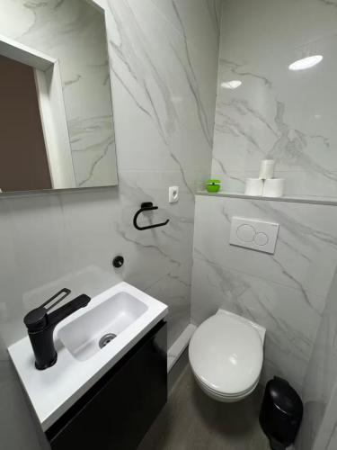 a white bathroom with a toilet and a sink at Stylish 1BR Apartment with Sofa Bed in the Heart of Liège in Liège
