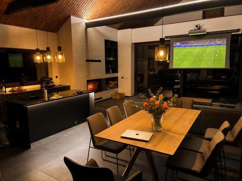 a dining room with a table and a large television at Chalet Beyond in Veľká Lomnica