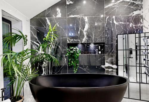a black tub in a bathroom with plants at Luxury Ascot Villa Steps from Royal Ascot, 5 mins to Legoland Windsor Resort, 10 mins to Windsor Castle in Ascot