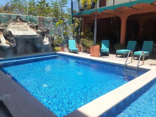 a swimming pool with blue chairs and a fireplace at "Le Petit Oasis" Pool, AC and Beach 1 minute away in La Peñita de Jaltemba