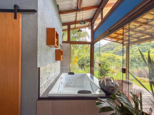 a bath tub in a room with a large window at Loft Pitangueira in Petrópolis
