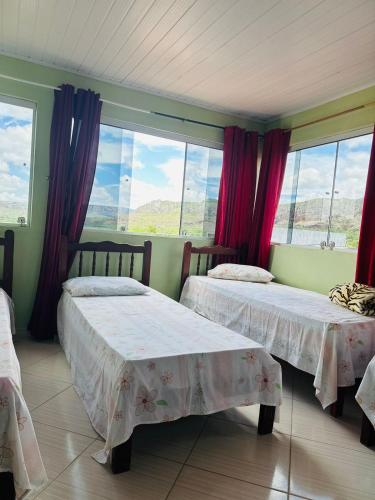 two beds in a room with windows at Pousada Vale do Catimbau in Buíque