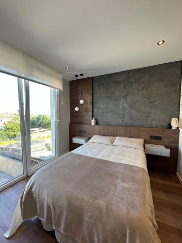 a bedroom with a large bed and a large window at Brisa de Sálvora in Ribeira