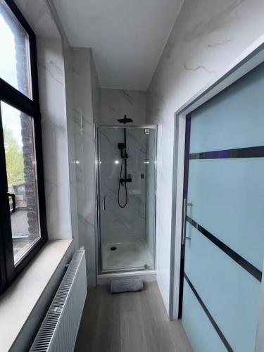 a bathroom with a shower with a glass door at Stylish 1BR Apartment Close to City Center Liège in Liège