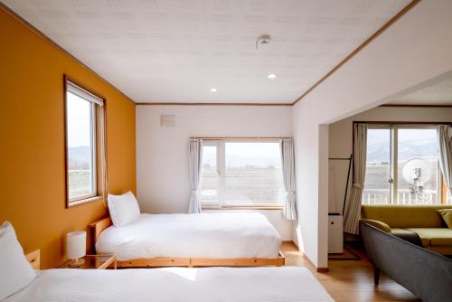 a bedroom with two beds and a couch and windows at House Of Joy Furano -15 mins to ski resort- in Furano