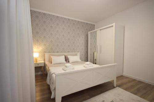 a white bedroom with a white bed and a mirror at Stan na dan Moonlight Panonija in Inđija