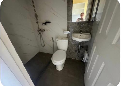 a woman taking a picture of a bathroom with a toilet and sink at Peipers Inn in Panglao Island