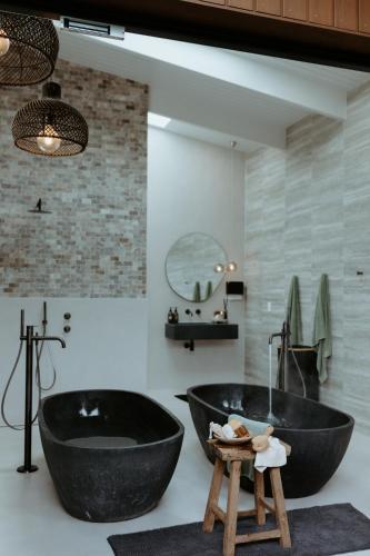 a bathroom with two black tubs and a sink at Te Whaanga Retreat & Spa in Raglan