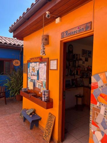 a store with an orange wall with a sign on it at Hostal El Punto in La Serena