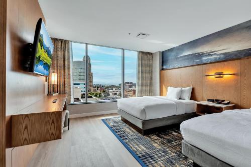 a hotel room with two beds and a flat screen tv at Embassy Suites Buffalo in Buffalo